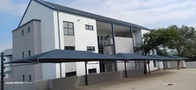 a white building with blue umbrellas in front of it at Chillasclub BNB-SAFUBI VIEWS in Nelspruit