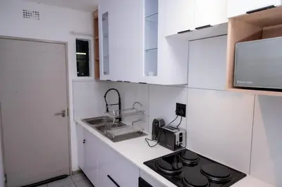 a white kitchen with a sink and a stove at 22 On End luxurious & modern yet private escape in Centurion