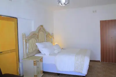 a bedroom with a white bed with white sheets and pillows at Comfort stay Guesthouse in Mokopane