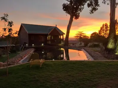 a house on the water with a sunset in the background at Kliphuisjes in Dullstroom