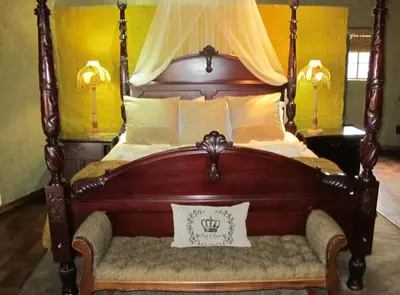 a canopy bed with a bench in a bedroom at Kliphuisjes in Dullstroom