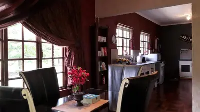 a dining room with a table and chairs and windows at Kliphuisjes in Dullstroom