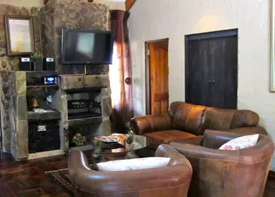 a living room with leather furniture and a fireplace at Kliphuisjes in Dullstroom