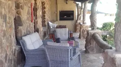 a patio with wicker chairs and a tv on a wall at Kliphuisjes in Dullstroom