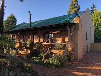 a large building with a green roof and a garden at Kliphuisjes in Dullstroom