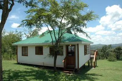 a small white house with a green roof at White House Lodge in White River