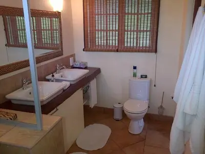 a bathroom with a toilet and two sinks and a mirror at White House Lodge in White River