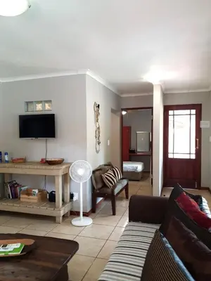 a living room with a couch and a tv at Gecko Cottages in Hectorspruit