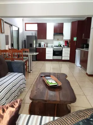 a living room with a table and a kitchen at Gecko Cottages in Hectorspruit