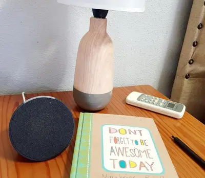 a book on a table with a lamp and a remote control at Gecko Cottages in Hectorspruit