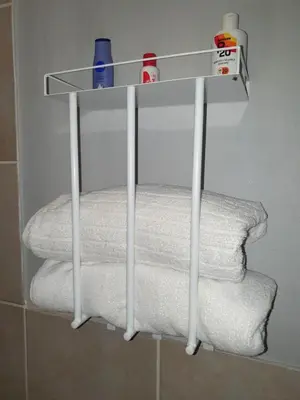 a white shelf with towels and toiletries in a bathroom at Gecko Cottages in Hectorspruit