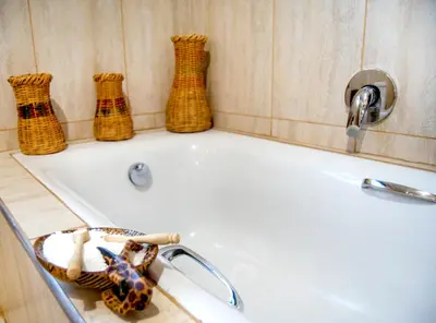 a bathroom with a bath tub with rattan vases at Sweni Lodge 91 Mjejane Kruger Park in Hectorspruit