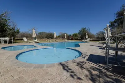a large swimming pool with chairs and umbrellas at Sweni Lodge 91 Mjejane Kruger Park in Hectorspruit