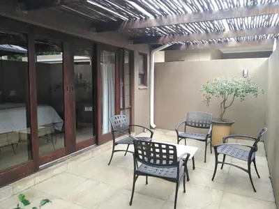 a patio with chairs and a table and a bed at Acacia Guest House in Nelspruit