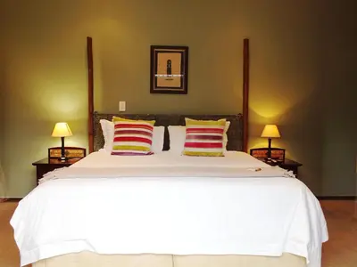 a bedroom with a large white bed with two lamps at Acacia Guest House in Nelspruit
