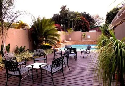 a group of chairs and tables on a deck next to a pool at Acacia Guest House in Nelspruit