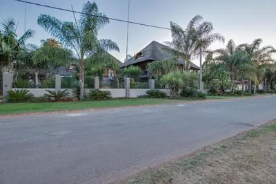 an empty street in front of a house with palm trees at Kassaboera Lodge in Hartbeespoort