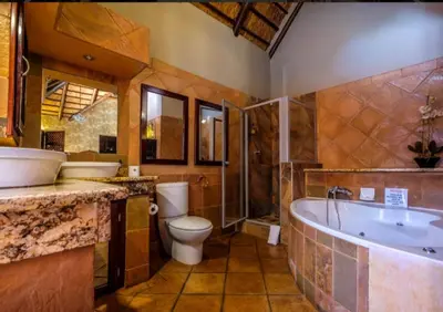 a bathroom with a tub and a toilet and a sink at Kassaboera Lodge in Hartbeespoort