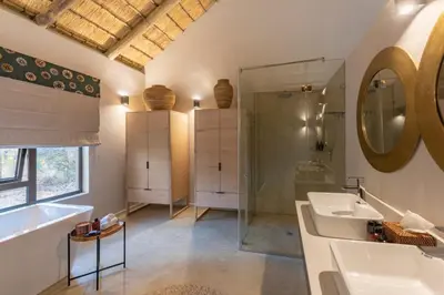 a bathroom with a sink and a tub and a mirror at Xanatseni Private Camp in Klaserie Private Nature Reserve