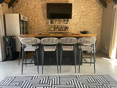 a bar with four chairs and a counter with a television at Xanatseni Private Camp in Klaserie Private Nature Reserve