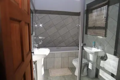 a bathroom with a tub and a sink and a toilet at Lodge Huge Dassie in Bela-Bela