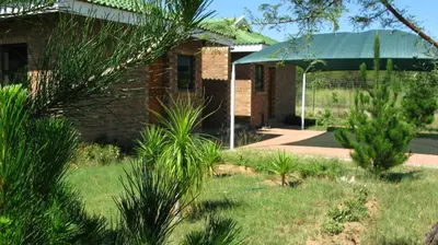 a house with plants in front of a yard at Lodge Huge Dassie in Bela-Bela
