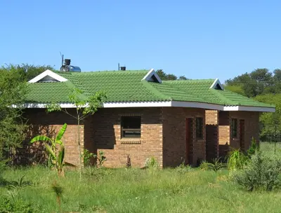 a brick house with a green roof at Lodge Huge Dassie in Bela-Bela