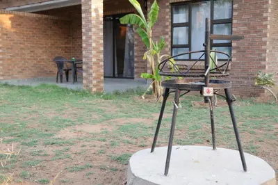 a metal chair sitting in a yard next to a building at Lodge Huge Dassie in Bela-Bela