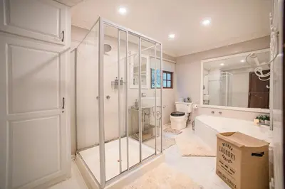 a white bathroom with a glass shower and a tub at Serenity Mountain and Forest Lodge in Malelane