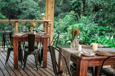 an outdoor dining area with tables and chairs on a deck at Serenity Mountain and Forest Lodge in Malelane