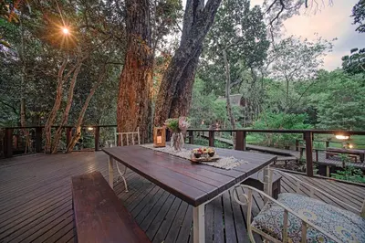 a wooden deck with a table and chairs on it at Serenity Mountain and Forest Lodge in Malelane