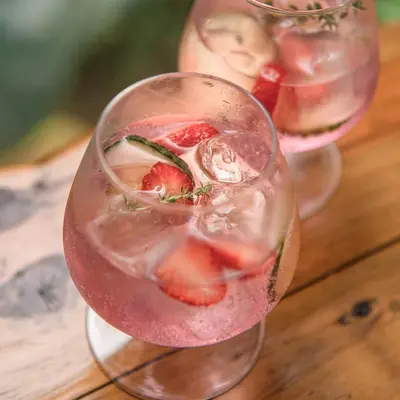 two wine glasses with strawberries in them on a wooden table at Serenity Mountain and Forest Lodge in Malelane