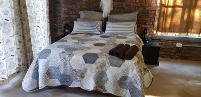 a bedroom with a bed with a quilt on it at Rio Dos Elefantes River Camp in Hoedspruit