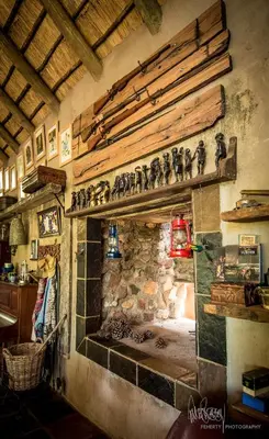 a room with a stone fireplace with figurines on the wall at Rio Dos Elefantes River Camp in Hoedspruit