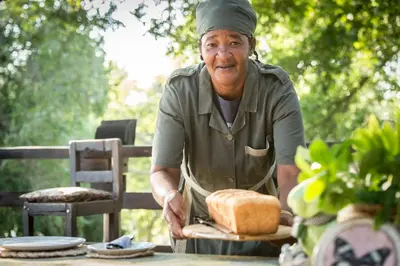 an older man is cutting a cake at a table at Rio Dos Elefantes River Camp in Hoedspruit