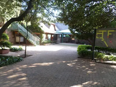 a brick road in front of a building with trees at Foundry Guest Lodge in Pretoria