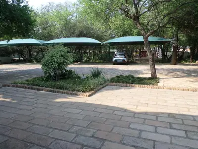 a parking lot with trees and blue umbrellas at Foundry Guest Lodge in Pretoria