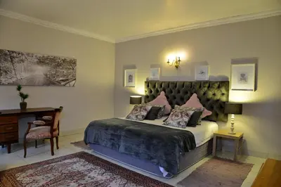 a bedroom with a large bed and a desk at Owls Loft Guest House in Midrand