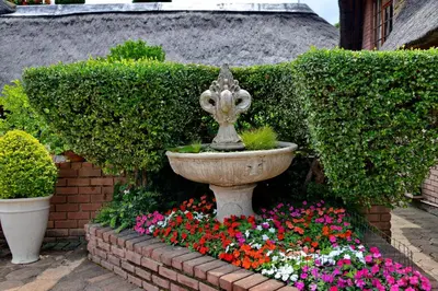 a garden with a fountain and flowers in a garden at Owls Loft Guest House in Midrand