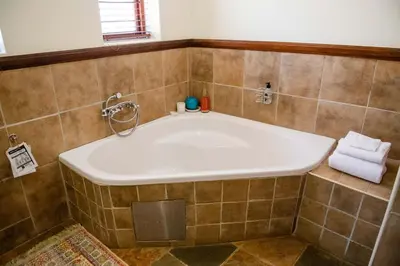 a large tub in a tiled bathroom with two towels at 37 on Charles in Pretoria