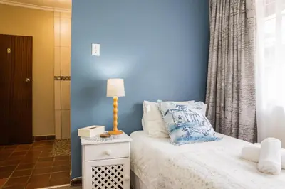 a bedroom with a bed with a blue wall at Rozendal Guest House in Centurion