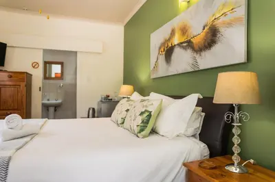 a bedroom with a white bed and a green wall at Rozendal Guest House in Centurion