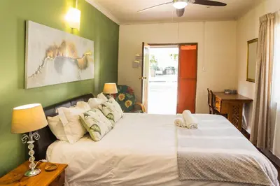 a bedroom with a white bed with a green wall at Rozendal Guest House in Centurion