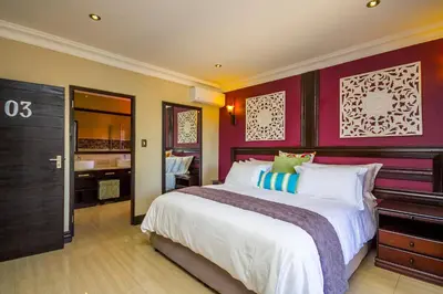 a bedroom with a large bed and a bathroom at Victorian Guest House in Nelspruit