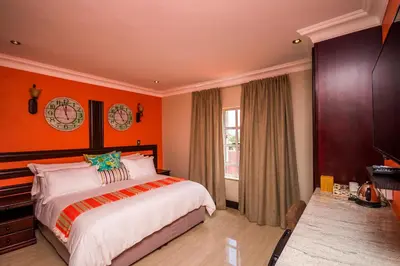a bedroom with orange walls and a large bed at Victorian Guest House in Nelspruit
