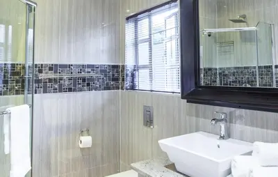 a bathroom with a sink and a glass shower at Victorian Guest House in Nelspruit