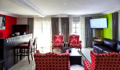 a living room with red chairs and a bar at Victorian Guest House in Nelspruit