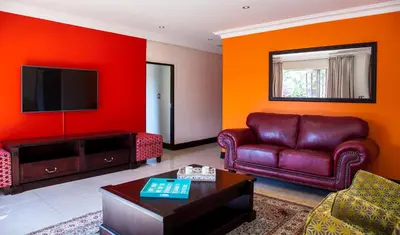 a living room with a couch and a tv at Victorian Guest House in Nelspruit