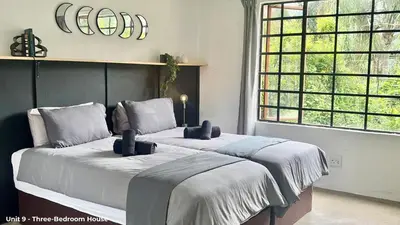 a bedroom with two beds and a large window at LoerieRoep Estate - Mountainview Selfcatering Accommodation Nelspruit in Nelspruit