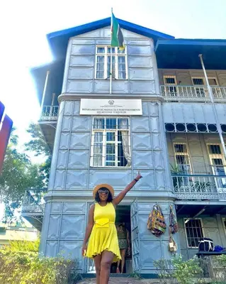 a woman in a yellow dress standing in front of a building at Villa-Candilabra Guesthouse in Komatipoort